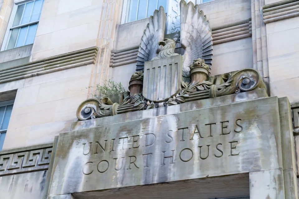 Close-up of carved United States Court House sign with eagle seal above a doorway.